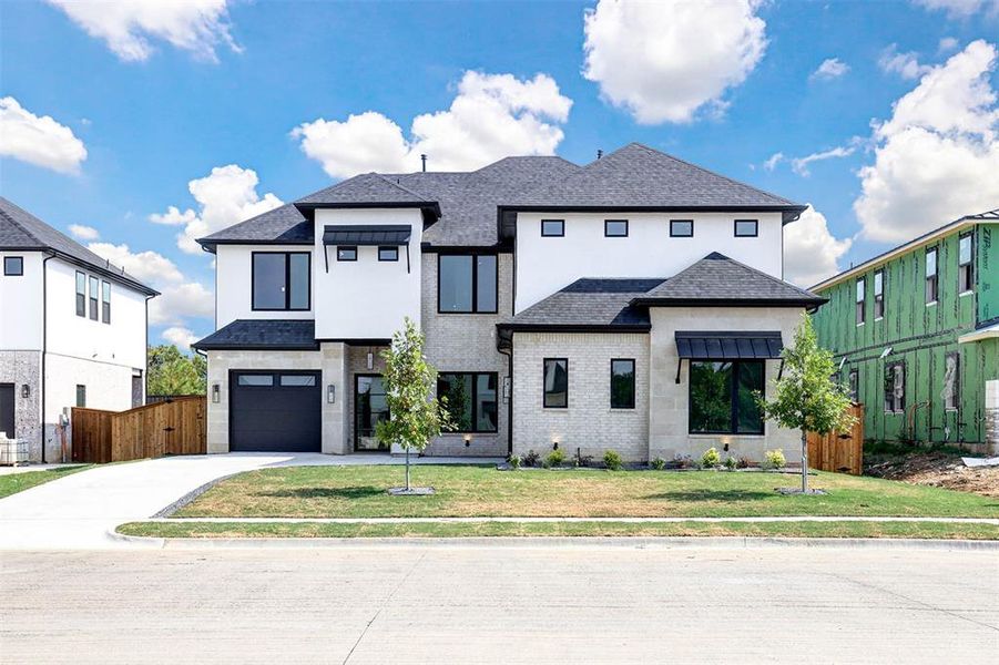 View of front facade featuring a garage and a front lawn