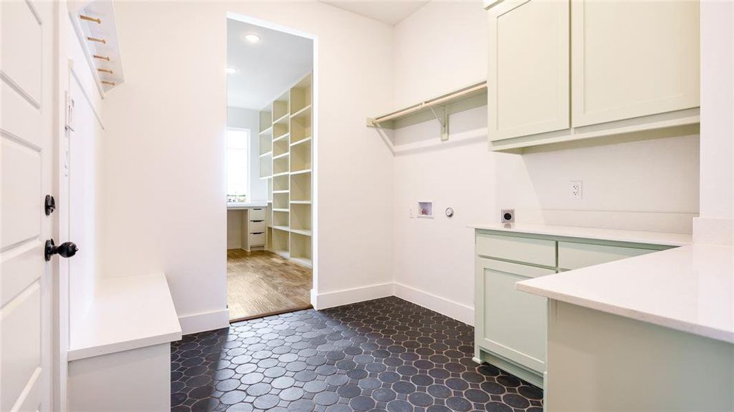 Laundry area with hookup for a washing machine, cabinets, electric dryer hookup, and dark tile floors