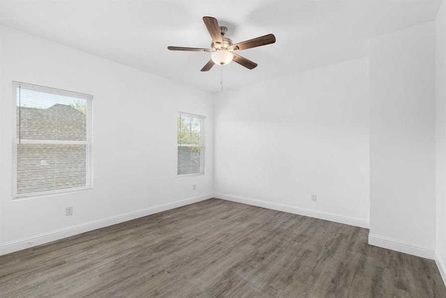 Unfurnished room featuring plenty of natural light, ceiling fan, and dark hardwood / wood-style flooring