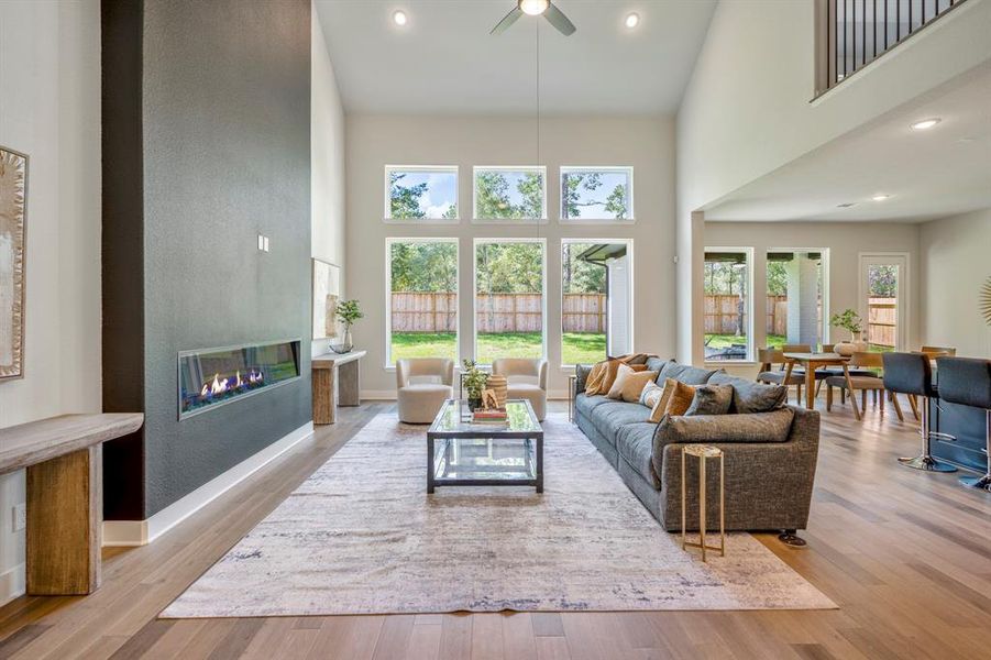 This beautiful living area boasts soaring ceilings, abundant natural light, and sleek fireplace.