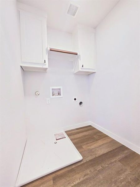 Washroom featuring washer hookup, cabinets, dark wood-type flooring, electric dryer hookup, and hookup for a gas dryer