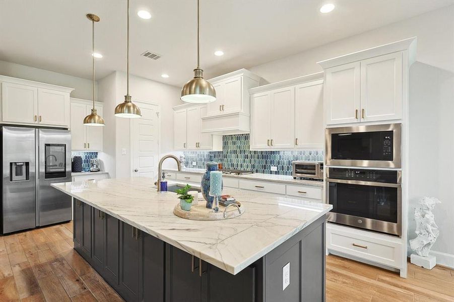 Kitchen featuring white cabinets, appliances with stainless steel finishes, and a center island with sink