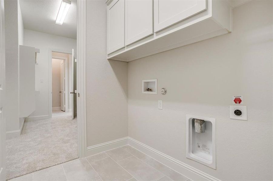 Washroom with hookup for a washing machine, hookup for a gas dryer, electric dryer hookup, cabinets, and light colored carpet