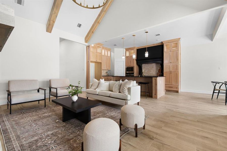 Living room with high vaulted ceiling, light hardwood / wood-style floors, beamed ceiling, and sink