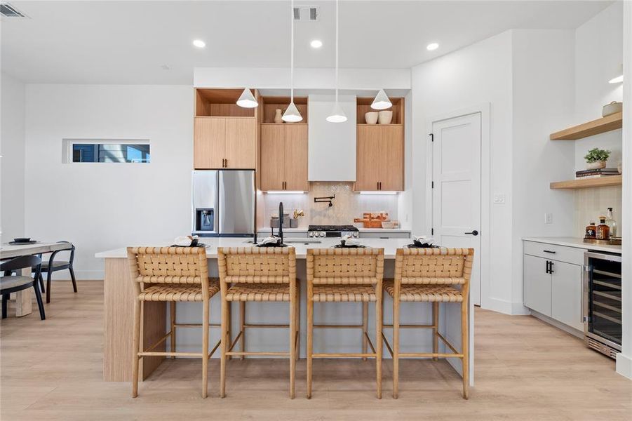 This kitchen impresses with its generous island, offering both seating and prep space, along with high-end finishes throughout. The warm wood cabinetry and sleek appliances create an ideal setting for culinary adventures, while the built-in wine cooler adds a touch of luxury, making it perfect for both intimate gatherings and lively entertaining.