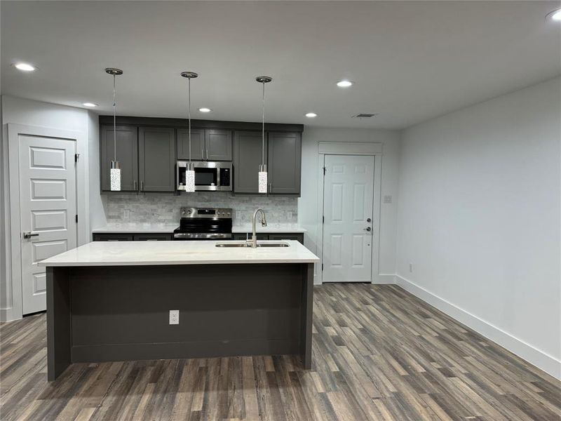 Kitchen with tasteful backsplash, stainless steel appliances, dark hardwood / wood-style flooring, sink, and gray cabinetry