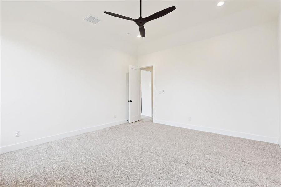 Empty room with ceiling fan and light carpet