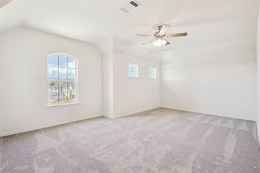 Carpeted empty room with ceiling fan and vaulted ceiling