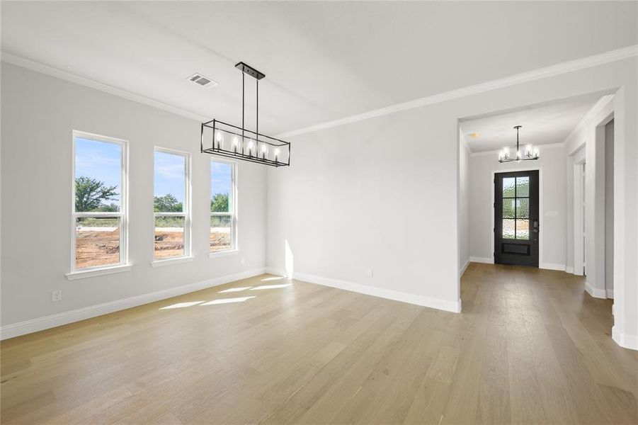 Unfurnished room featuring ornamental molding, light hardwood / wood-style floors, and an inviting chandelier