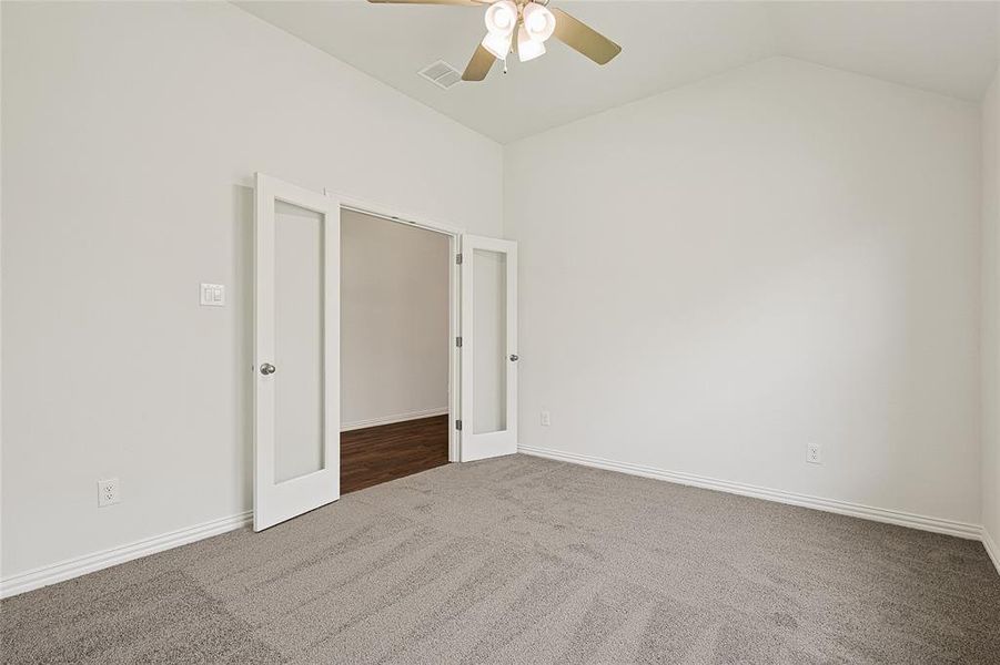 Spare room featuring lofted ceiling, carpet, and ceiling fan