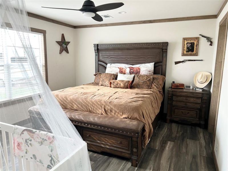 Bedroom with dark wood-type flooring, ceiling fan, and crown molding