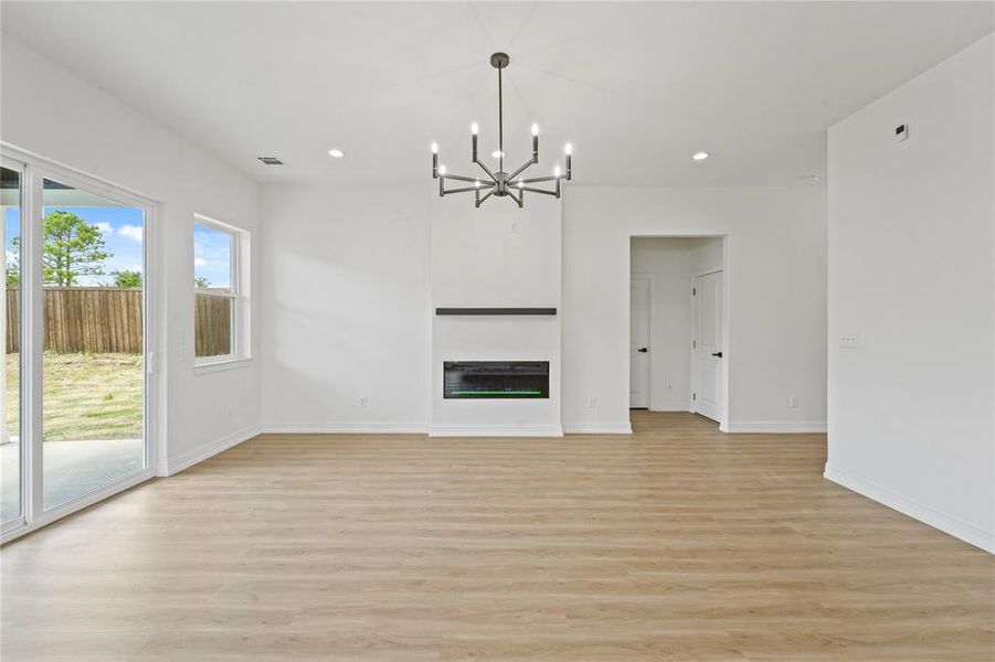 Unfurnished living room with light hardwood / wood-style floors and a chandelier