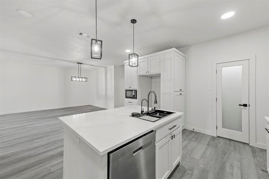 Kitchen with a center island with sink, sink, white cabinets, and dishwasher