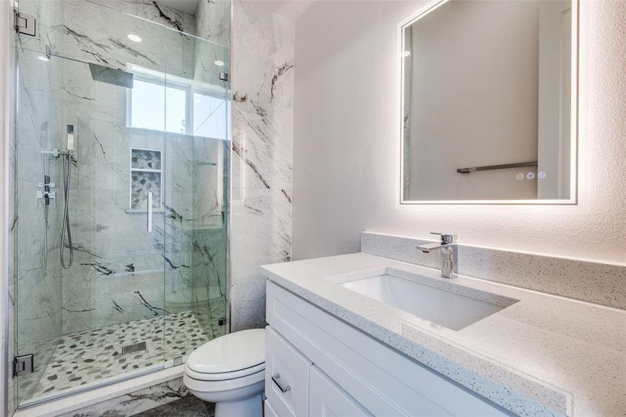 Bathroom with walk in shower, toilet, and vanity with extensive cabinet space
