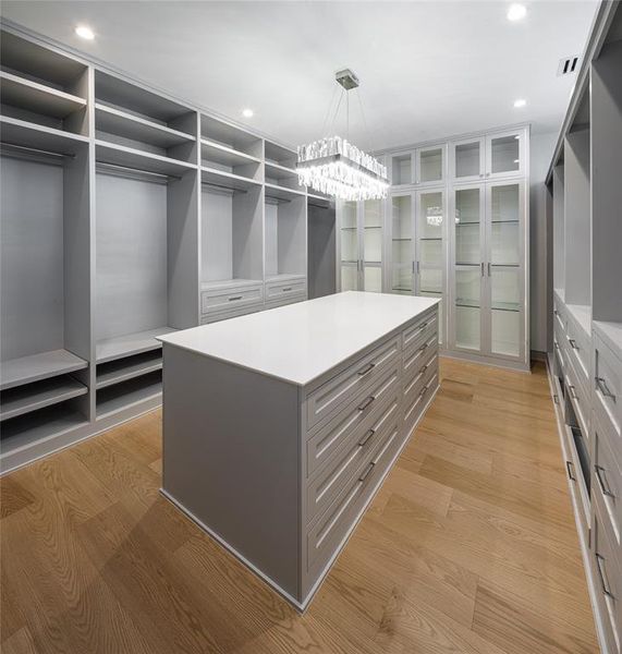 Ladies' dressing room with custom built-ins, center island with drawers and an elegant crystal chandelier