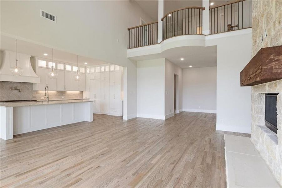 Unfurnished living room with a towering ceiling, light hardwood / wood-style flooring, a fireplace, and sink