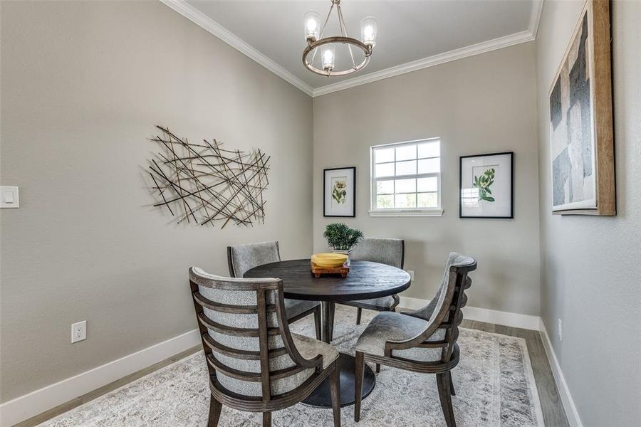 Dining space with crown molding, a chandelier, and light hardwood / wood-style flooring