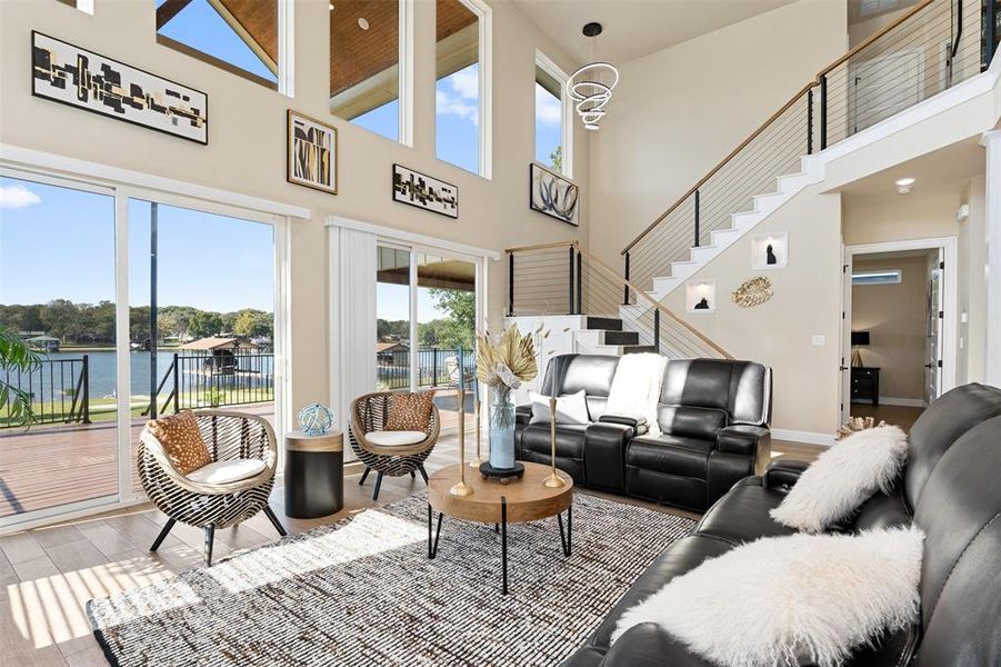 Living room with a towering ceiling, a water view, and light hardwood / wood-style flooring