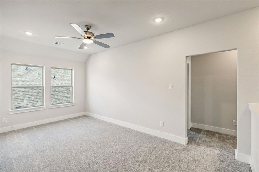 Spare room featuring lofted ceiling, ceiling fan, and light carpet