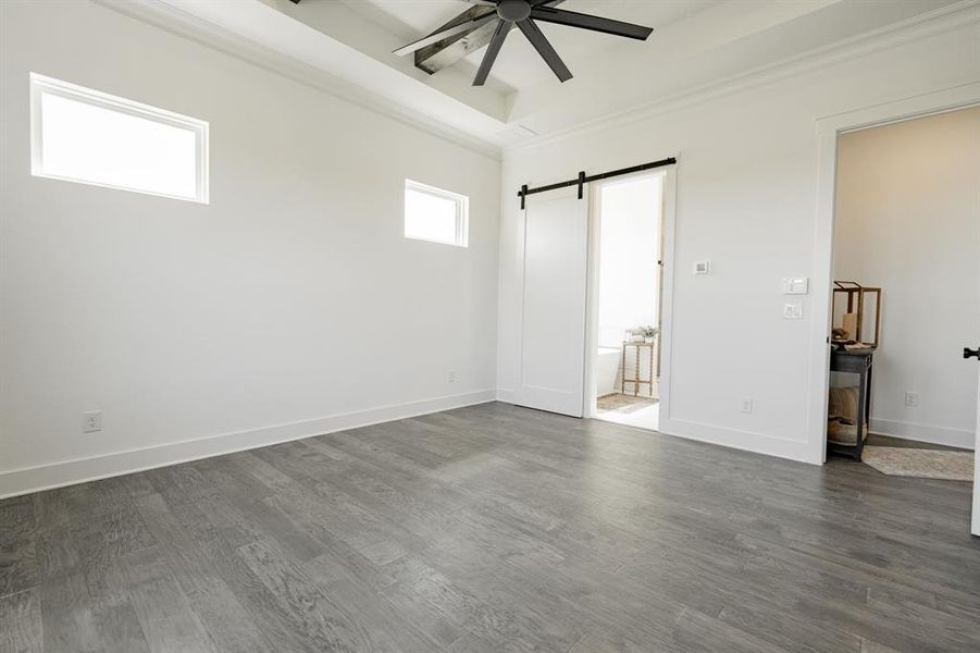 Master room with ornamental molding, ceiling fan, dark hardwood / wood-style floors, and a barn door