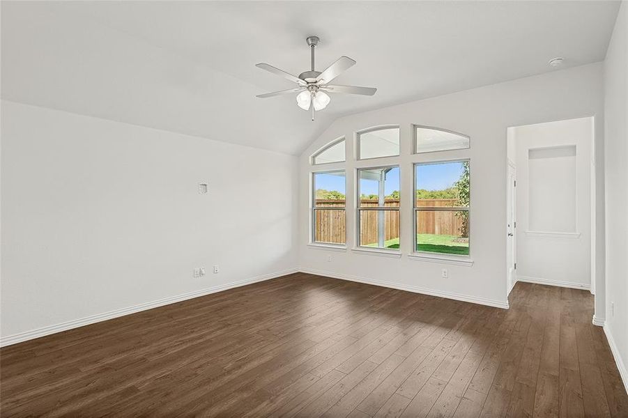 Empty room with ceiling fan, lofted ceiling, and dark hardwood / wood-style floors