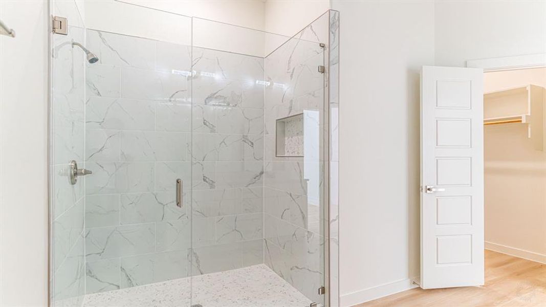 Tiled shower and large walk in closet in primary bath