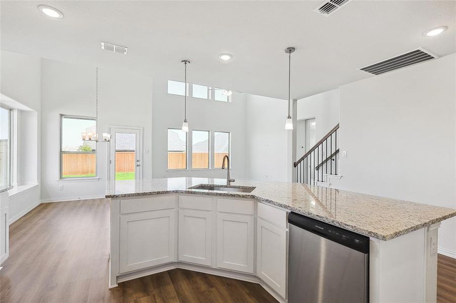 Kitchen with sink, stainless steel dishwasher, white cabinetry, dark hardwood / wood-style floors, and an inviting chandelier