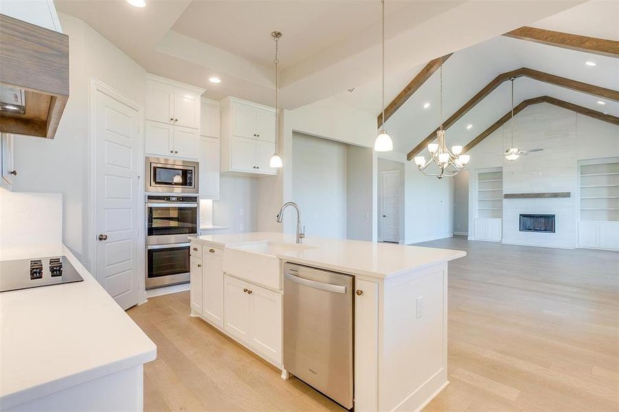 Kitchen featuring a kitchen island with sink, range hood, appliances with stainless steel finishes, and light wood-type flooring