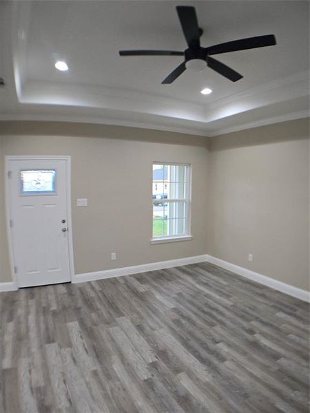 Foyer featuring ceiling fan, a tray ceiling, crown molding, and wood-type flooring