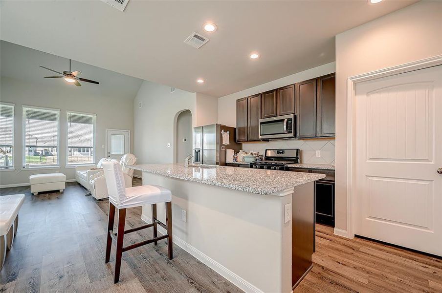 The kitchen dazzles with sleek countertops that provide both beauty and functionality. The island offers ample workspace and includes a stylish breakfast bar, perfect for casual meals or entertaining guests.