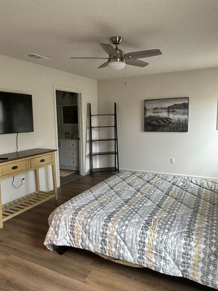 Bedroom with connected bathroom, dark hardwood / wood-style flooring, and ceiling fan