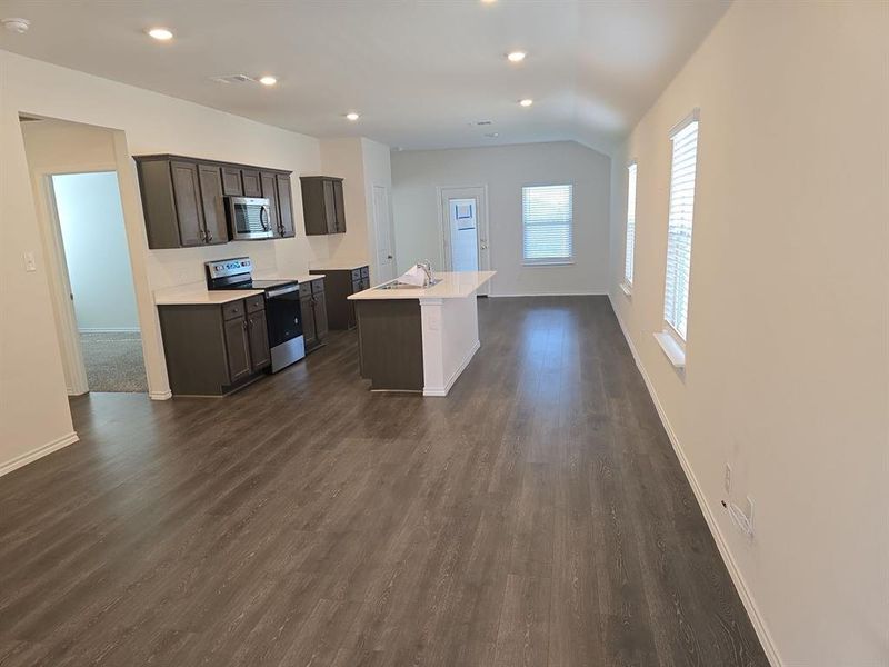 Kitchen with vaulted ceiling, stainless steel appliances, a kitchen island with sink, dark hardwood / wood-style floors, and sink