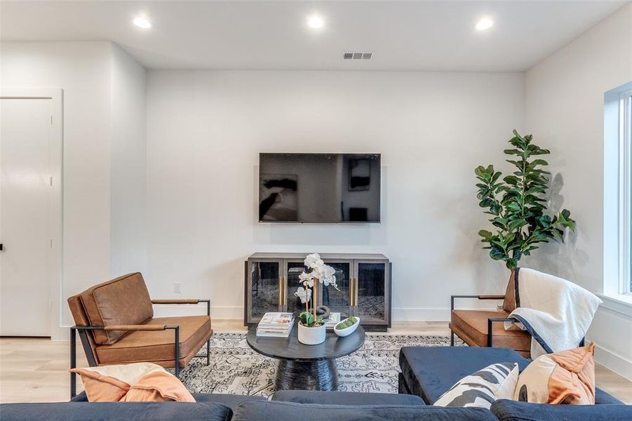 Living room featuring light wood-type flooring and a high end fireplace