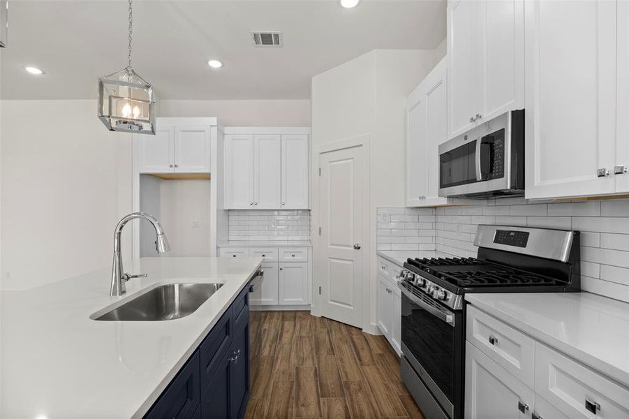 Kitchen featuring appliances with stainless steel finishes, sink, backsplash, white cabinetry, and dark wood-type flooring