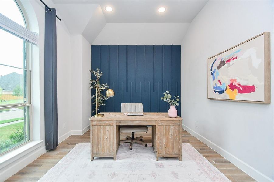 Bright and airy home office space featuring a bold blue accent wall. Large windows provide plenty of natural light, and the room's high ceiling adds a sense of spaciousness.