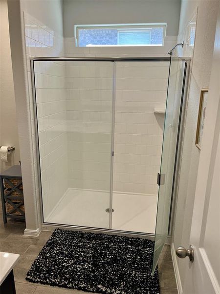 Bathroom with vanity, a wealth of natural light, a shower with shower door, and tile patterned flooring