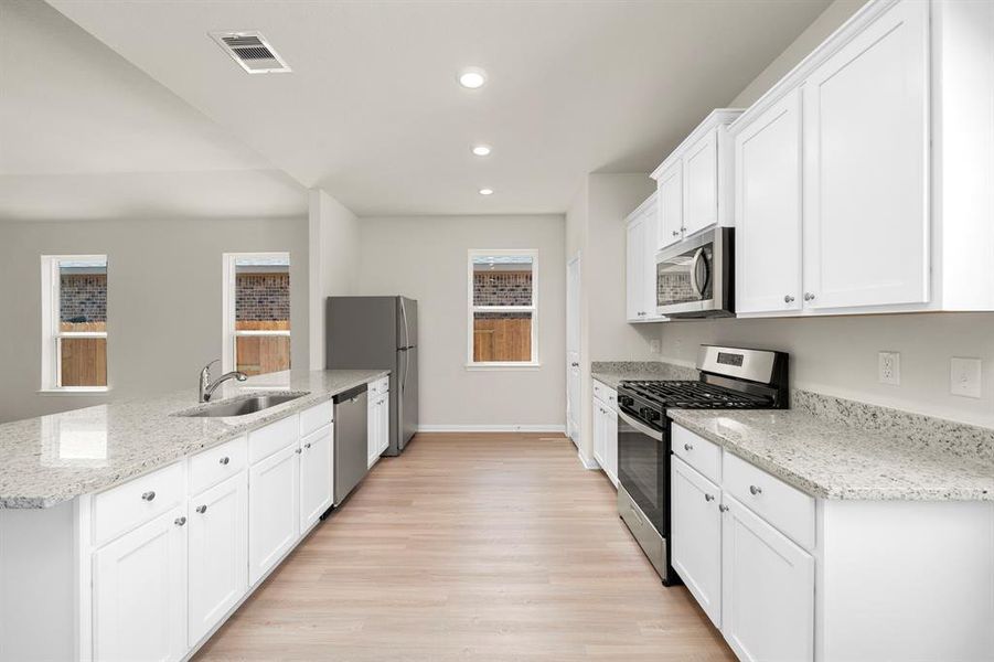 The kitchen features plenty of storage space with the stylish white cabinetry.