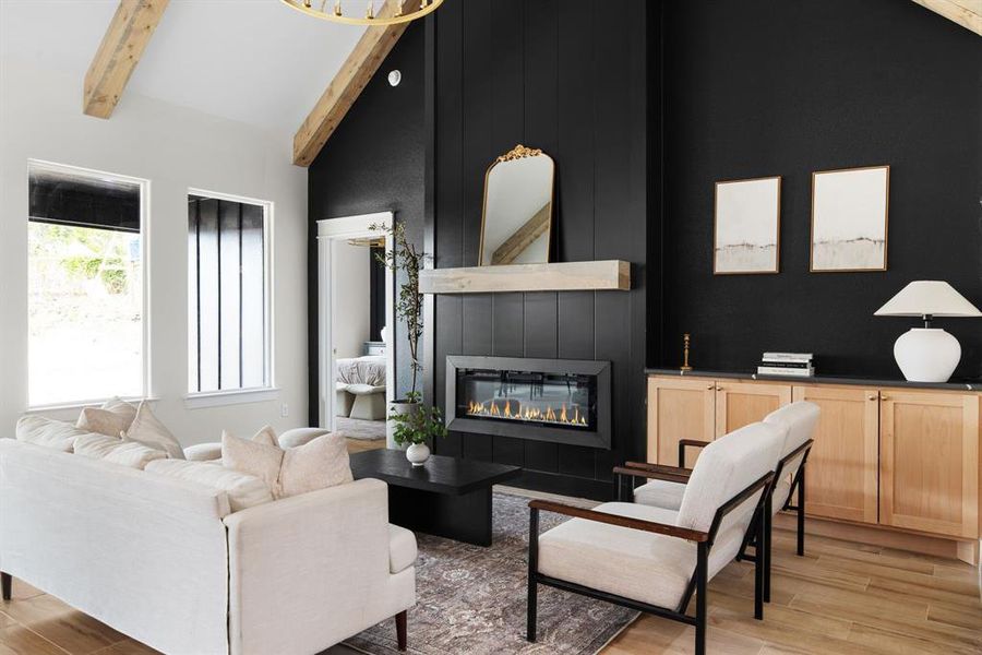 Living room featuring high vaulted ceiling, light wood-type flooring, beam ceiling, and a fireplace