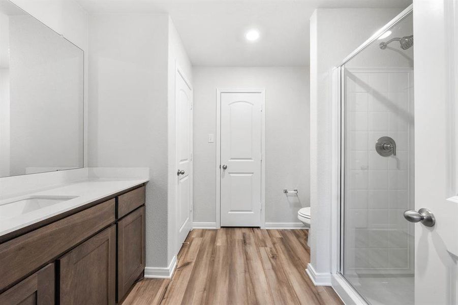 Bathroom featuring a shower with shower door, wood-type flooring, toilet, and vanity