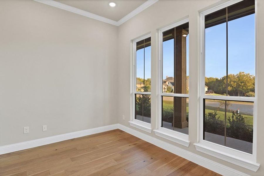 Spare room featuring ornamental molding and light hardwood / wood-style floors