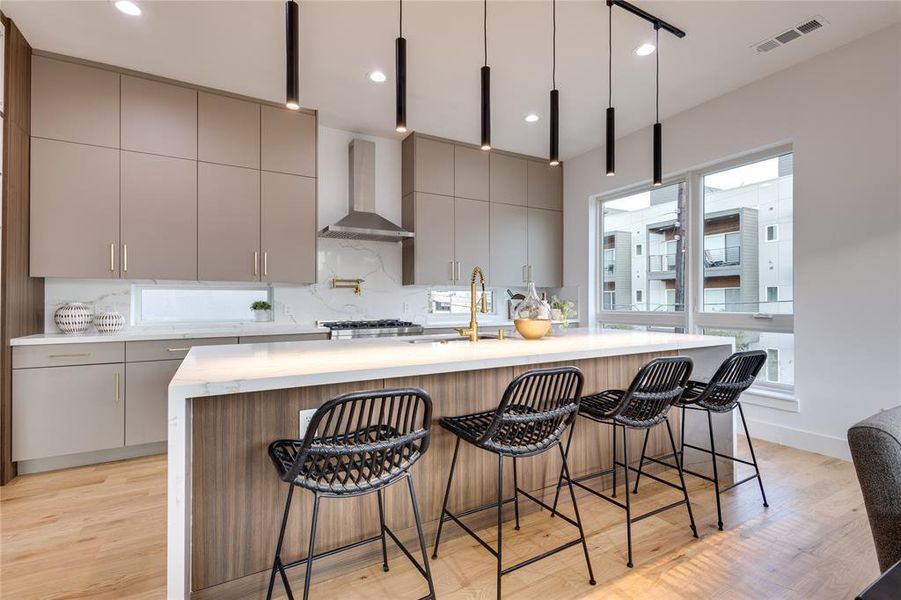 Kitchen featuring an island with sink, light wood-type flooring, wall chimney exhaust hood, and sink