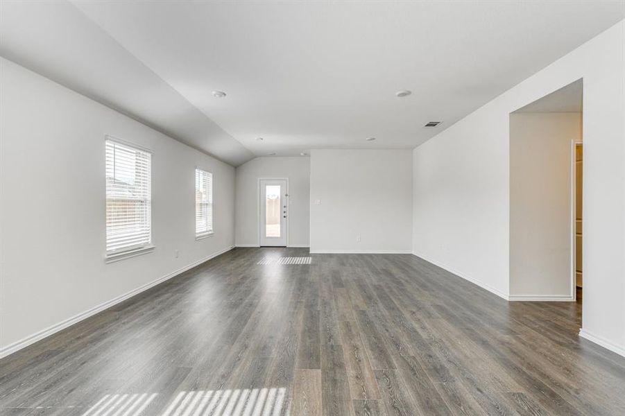 Empty room with vaulted ceiling and dark hardwood / wood-style floors