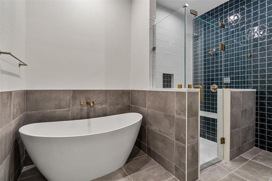 Bathroom with tile patterned flooring, tile walls, and shower with separate bathtub