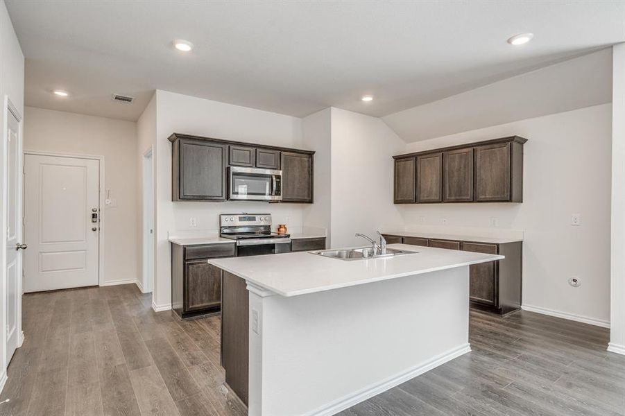 Kitchen with dark brown cabinetry, sink, a center island with sink, appliances with stainless steel finishes, and light wood-type flooring