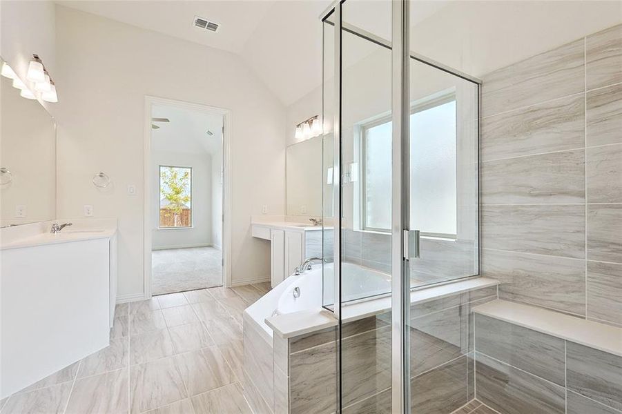 Bathroom featuring vanity, lofted ceiling, and separate shower and tub