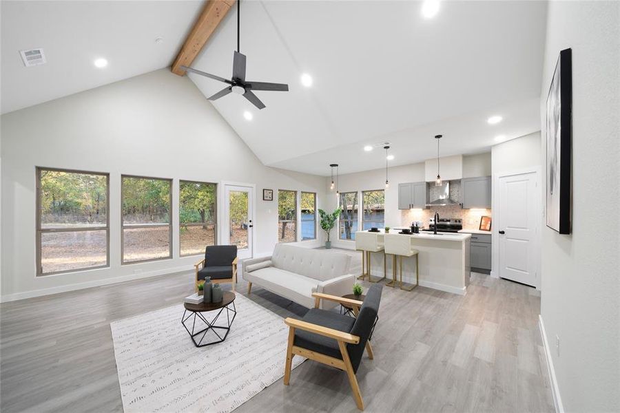 Living room with sink, light hardwood / wood-style floors, ceiling fan, beam ceiling, and high vaulted ceiling