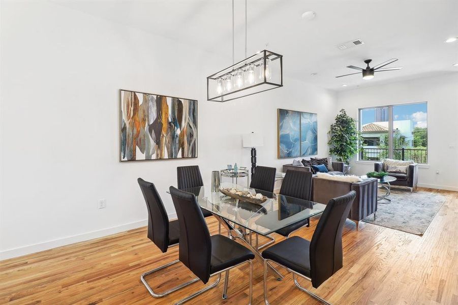 Dining room with light wood-type flooring and ceiling fan with notable chandelier