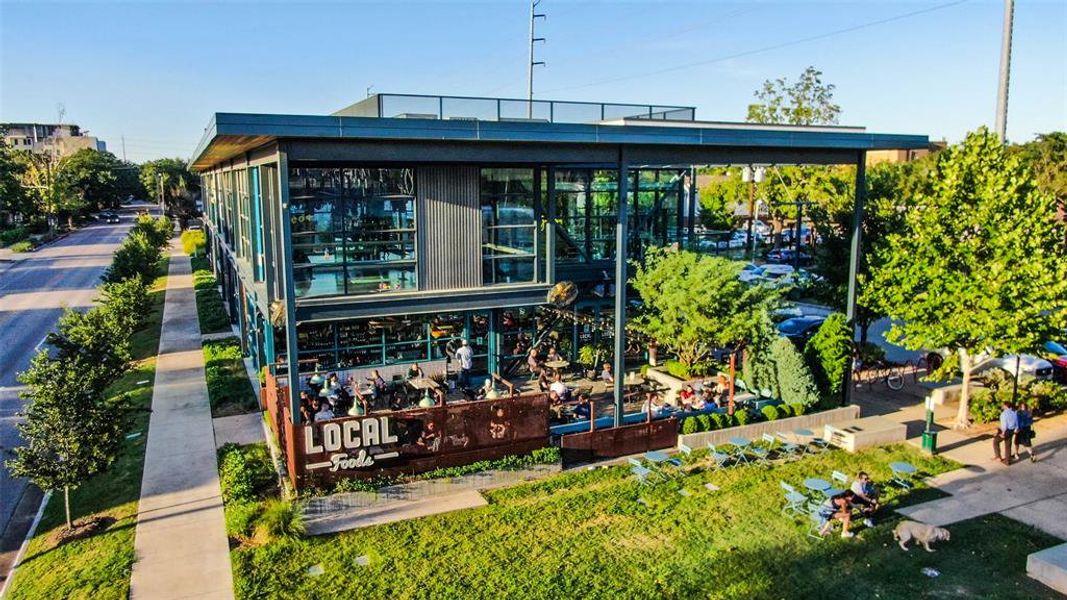 A bustling area retail hub with a popular restaurant, patio seating, greenery, and a vibrant atmosphere for locals and visitors alike.
