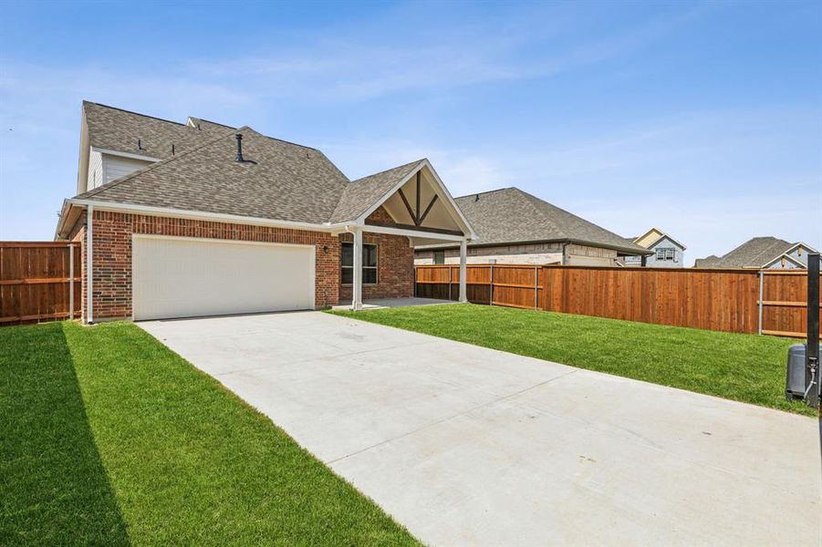 View of front facade featuring a garage and a front lawn