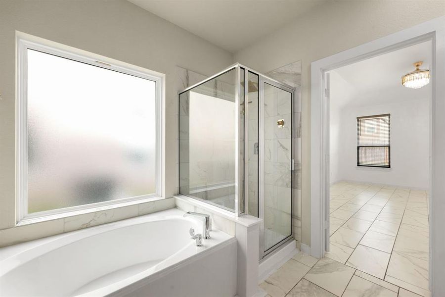 This additional view of the primary bath showcases a walk-in shower with tile surround and a separate garden tub perfect for soaking after a long day.